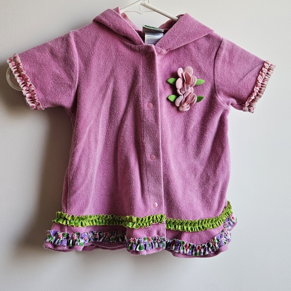 Pink swimsuit cover with flowers and ruffles.  It has a snap closure and a hood.